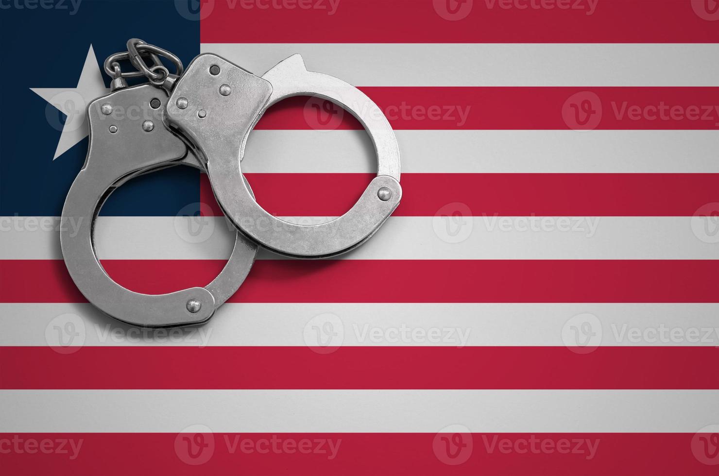 Liberia flag  and police handcuffs. The concept of crime and offenses in the country photo