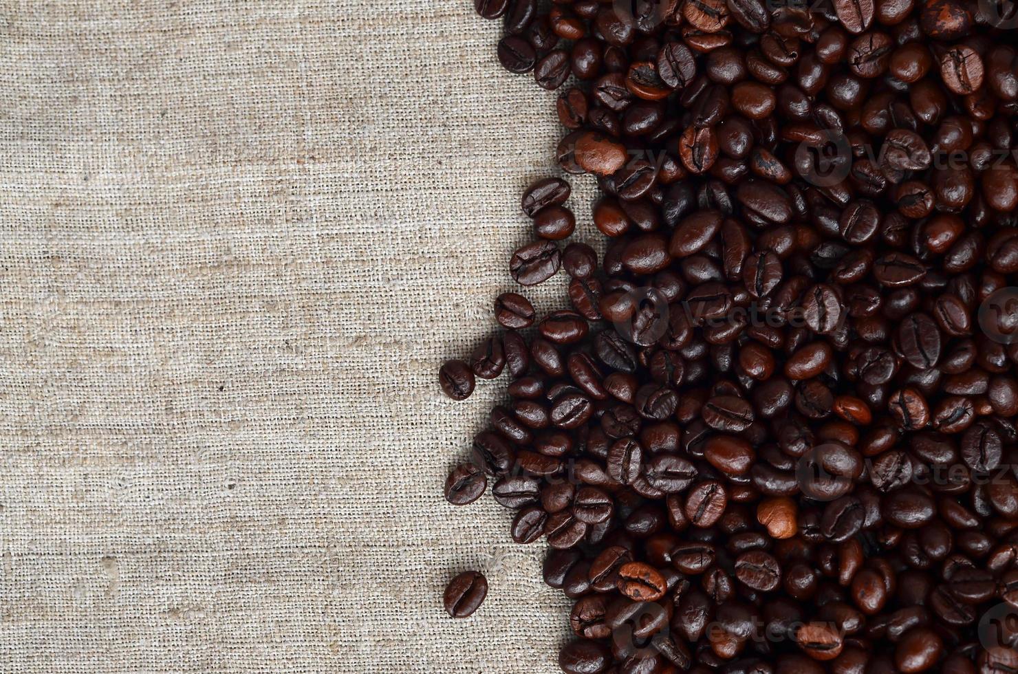 Texture of a gray canvas made of old and coarse burlap with coffee beans on it photo