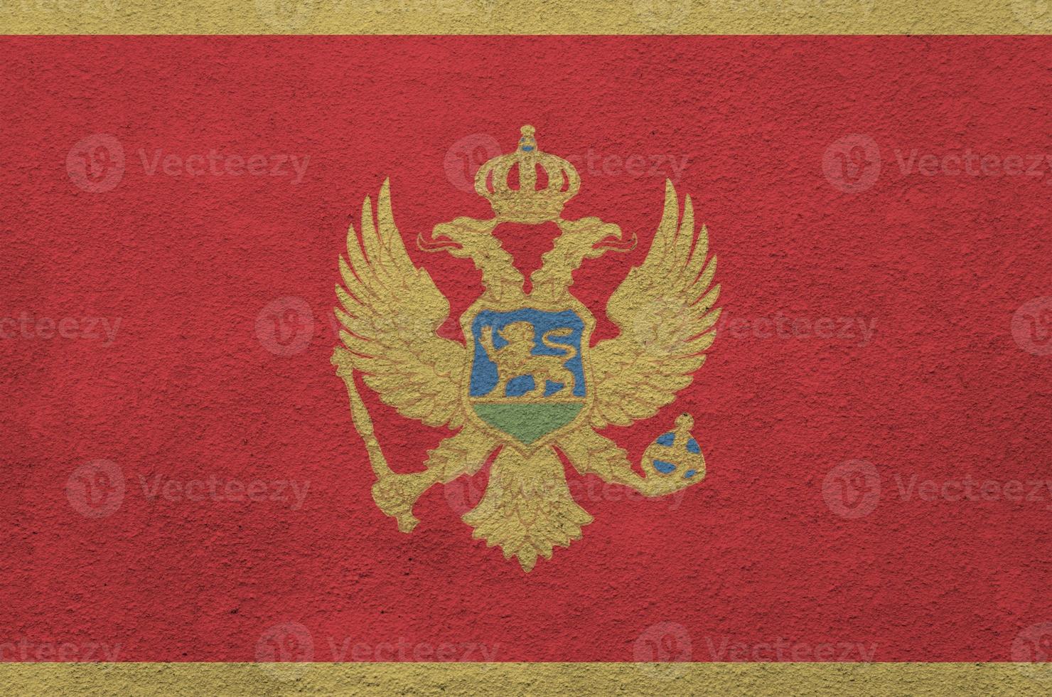 Montenegro flag depicted in bright paint colors on old relief plastering wall. Textured banner on rough background photo