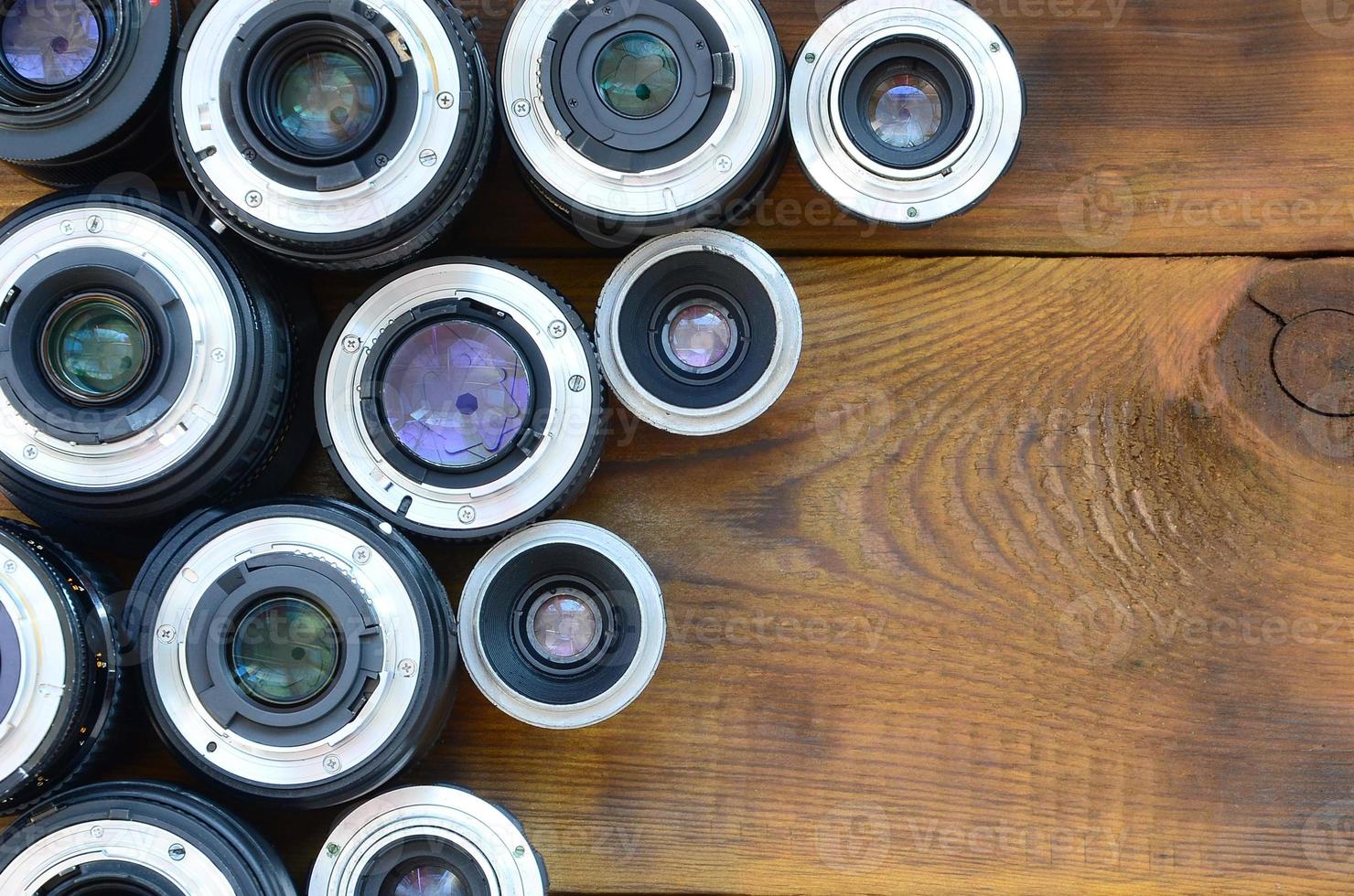 varias lentes fotográficas yacen sobre un fondo de madera marrón. espacio para texto foto