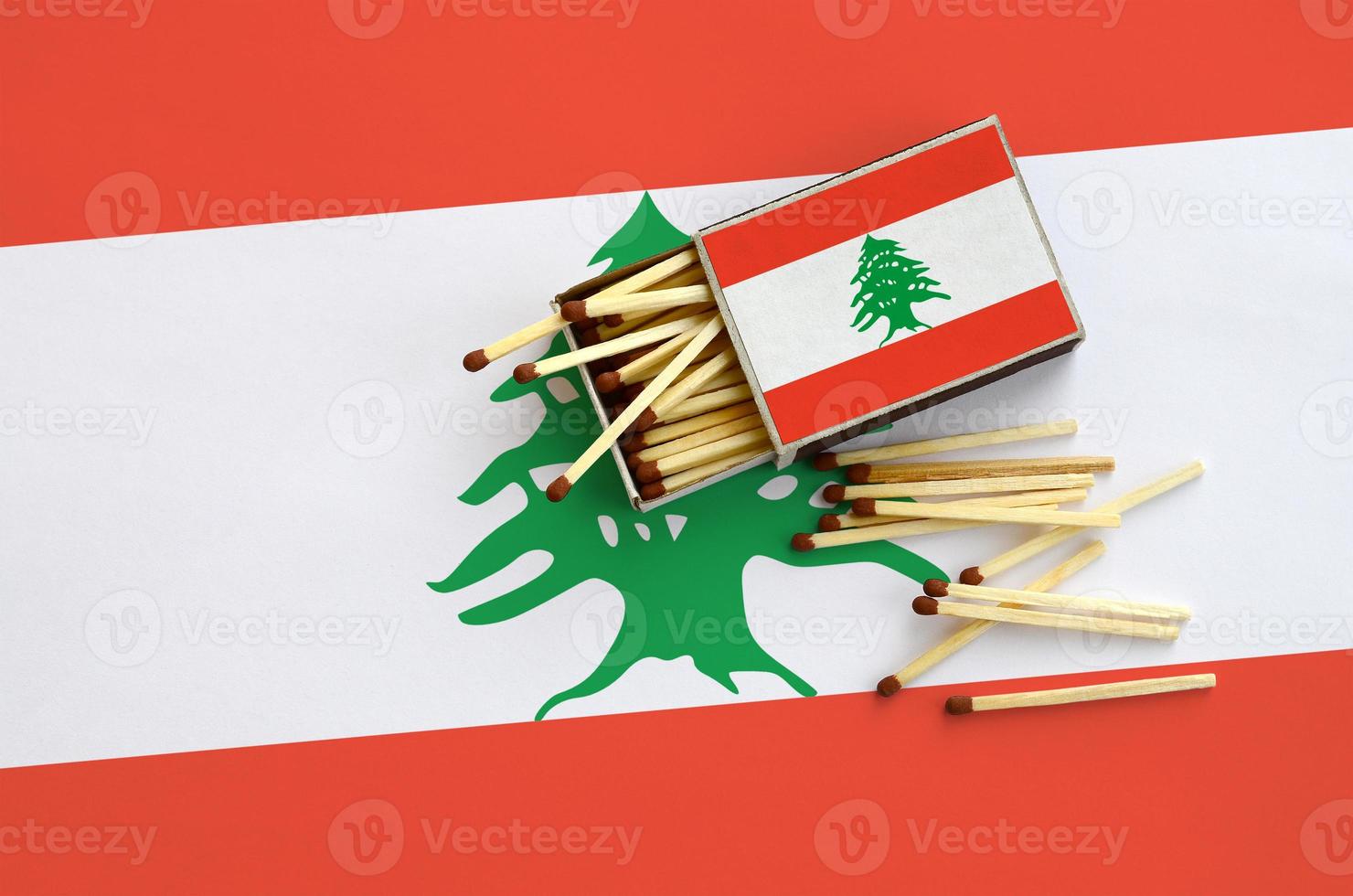 Lebanon flag  is shown on an open matchbox, from which several matches fall and lies on a large flag photo