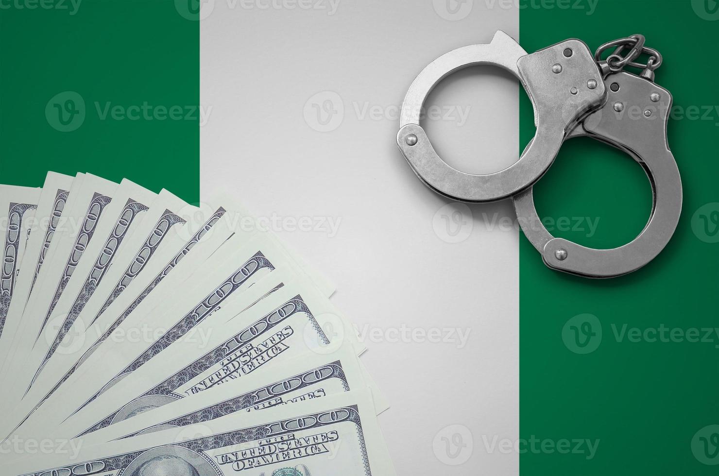Nigeria flag  with handcuffs and a bundle of dollars. The concept of illegal banking operations in US currency photo
