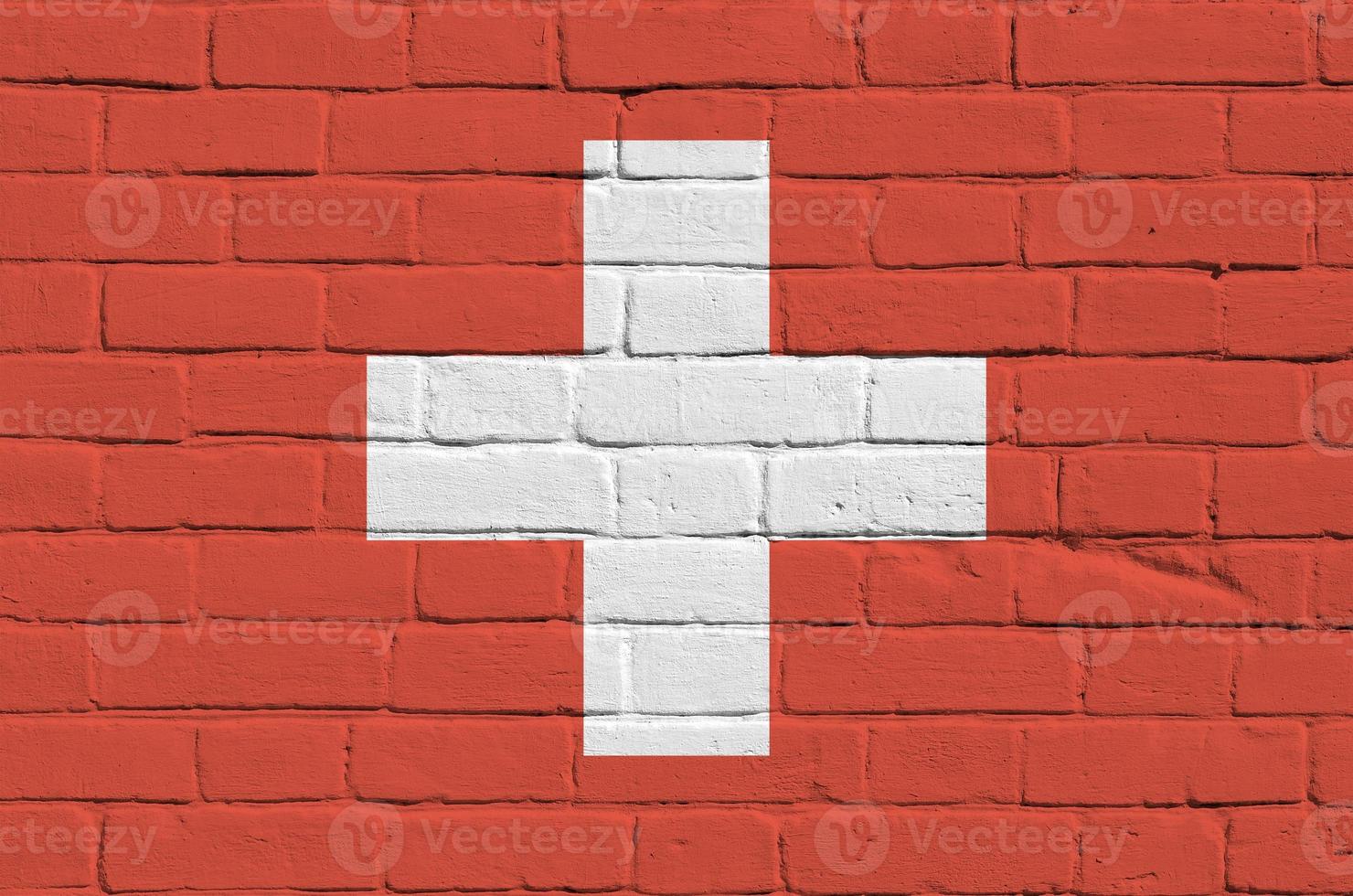 Switzerland flag depicted in paint colors on old brick wall. Textured banner on big brick wall masonry background photo