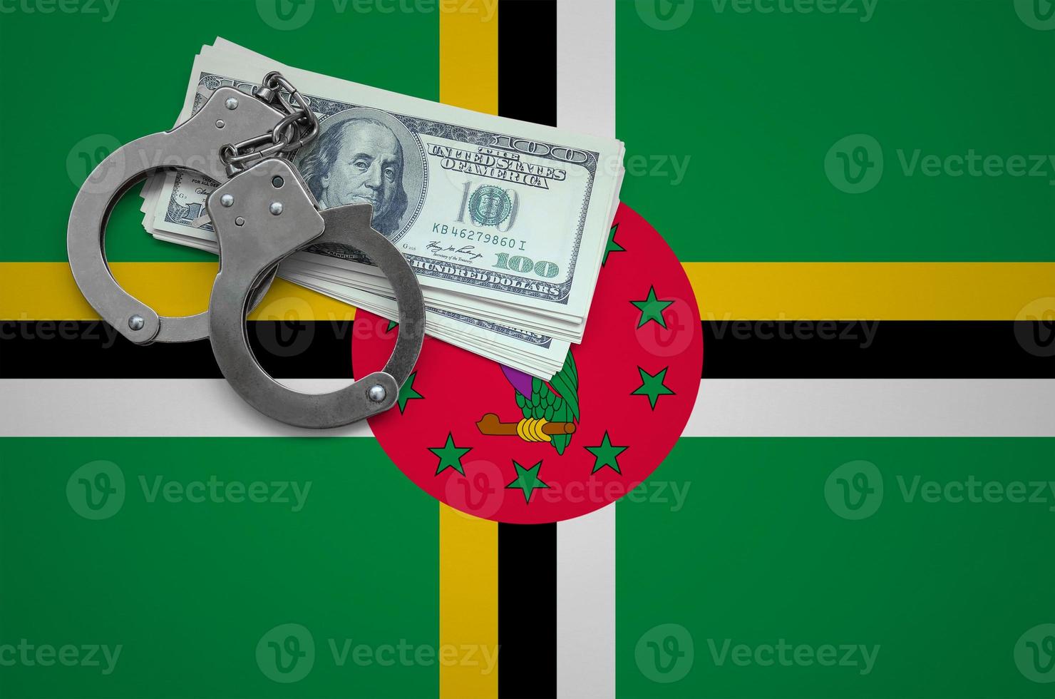 Dominica flag  with handcuffs and a bundle of dollars. The concept of breaking the law and thieves crimes photo