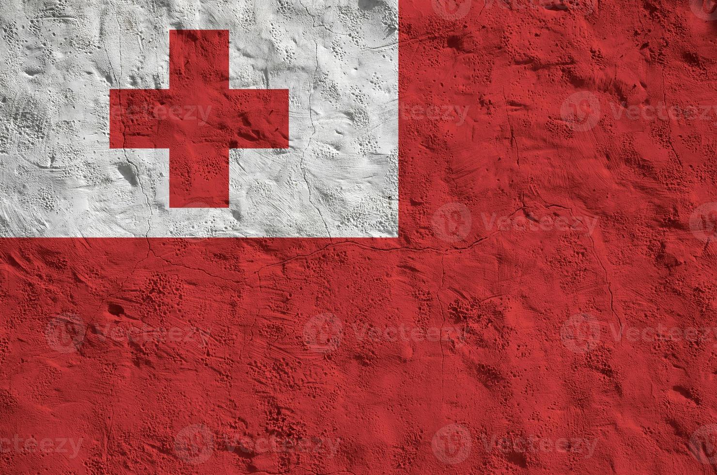 Tonga flag depicted in bright paint colors on old relief plastering wall. Textured banner on rough background photo
