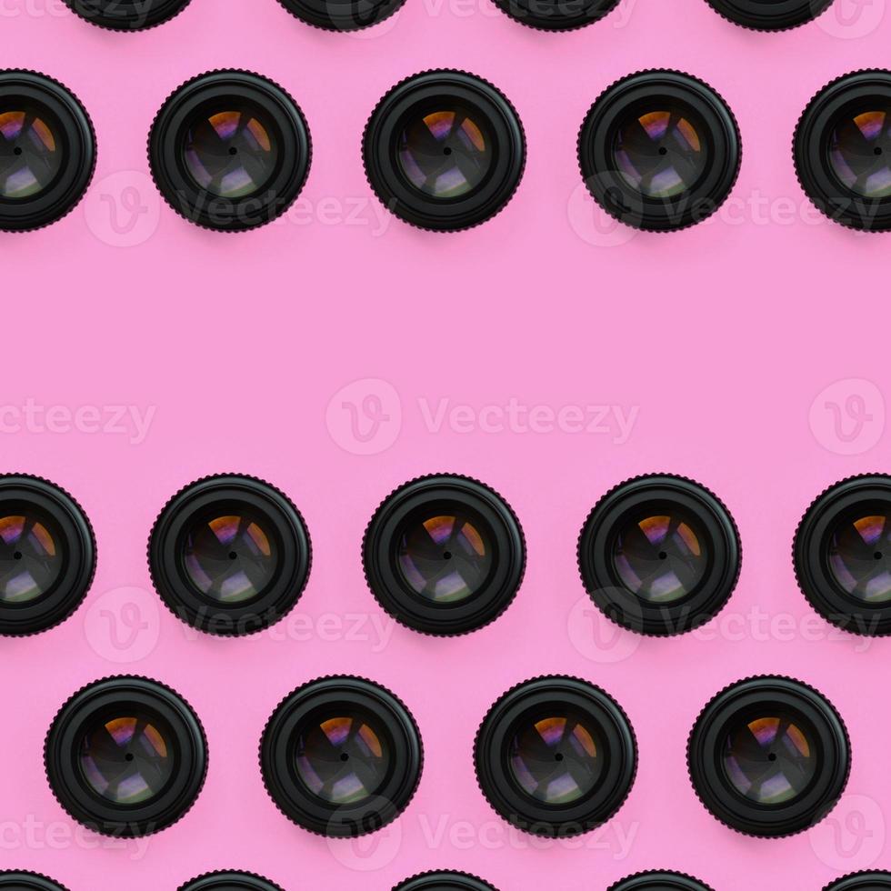 A few camera lenses with a closed aperture lie on texture background of fashion pastel pink color paper in minimal concept. Abstract trendy pattern photo