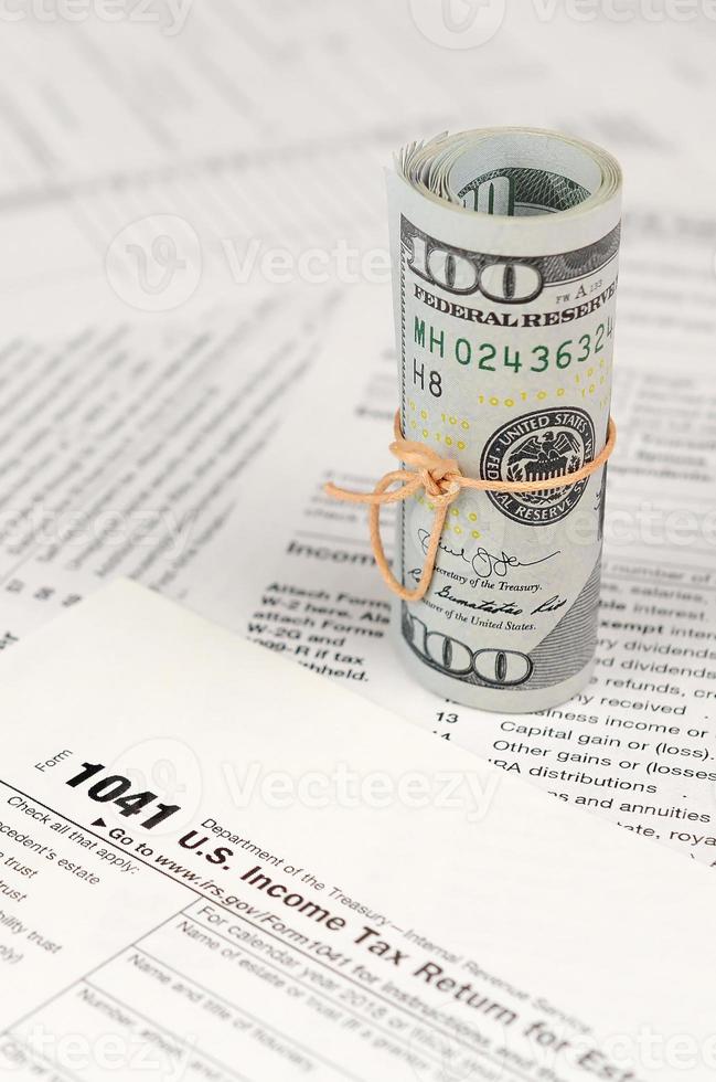 Formulario de declaración de impuestos sobre la renta de 1041 us para sucesiones y fideicomisos con rollo de billetes de dólar americano foto