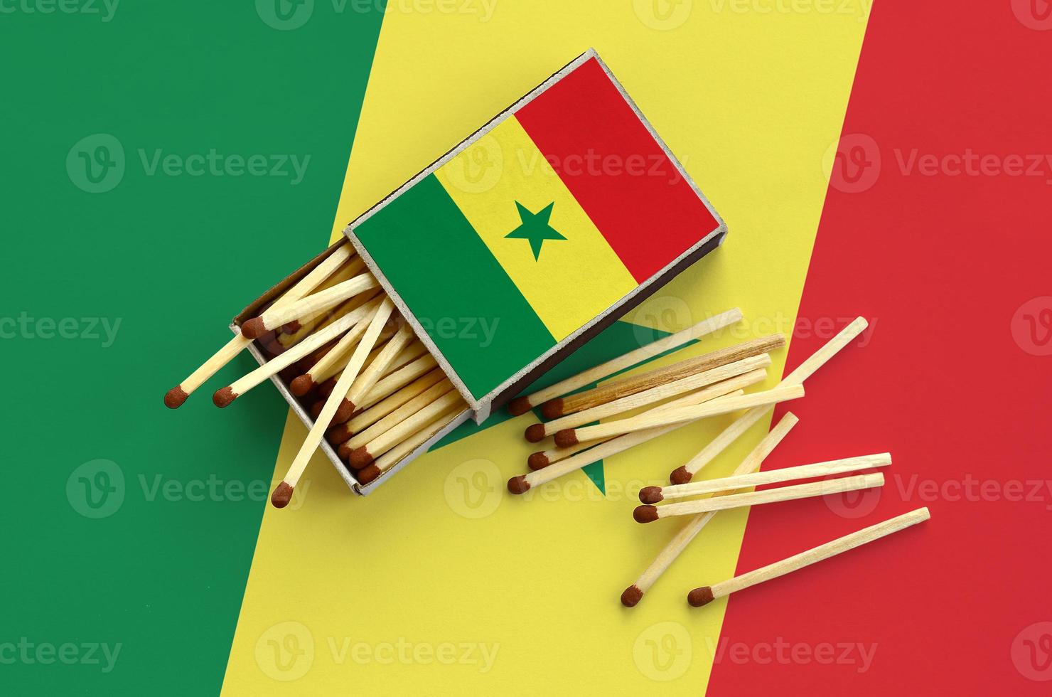 Senegal flag  is shown on an open matchbox, from which several matches fall and lies on a large flag photo