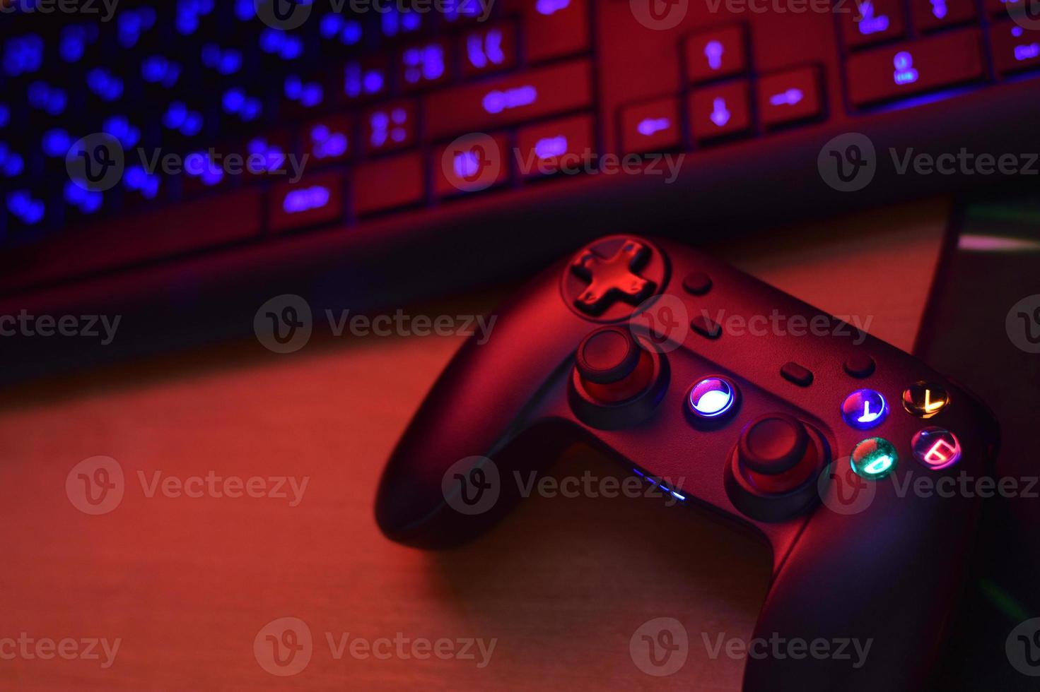 Modern gamepad lies with pc keyboard on table in dark playroom scene. Gameplay streaming and video game walkthroughts concept photo