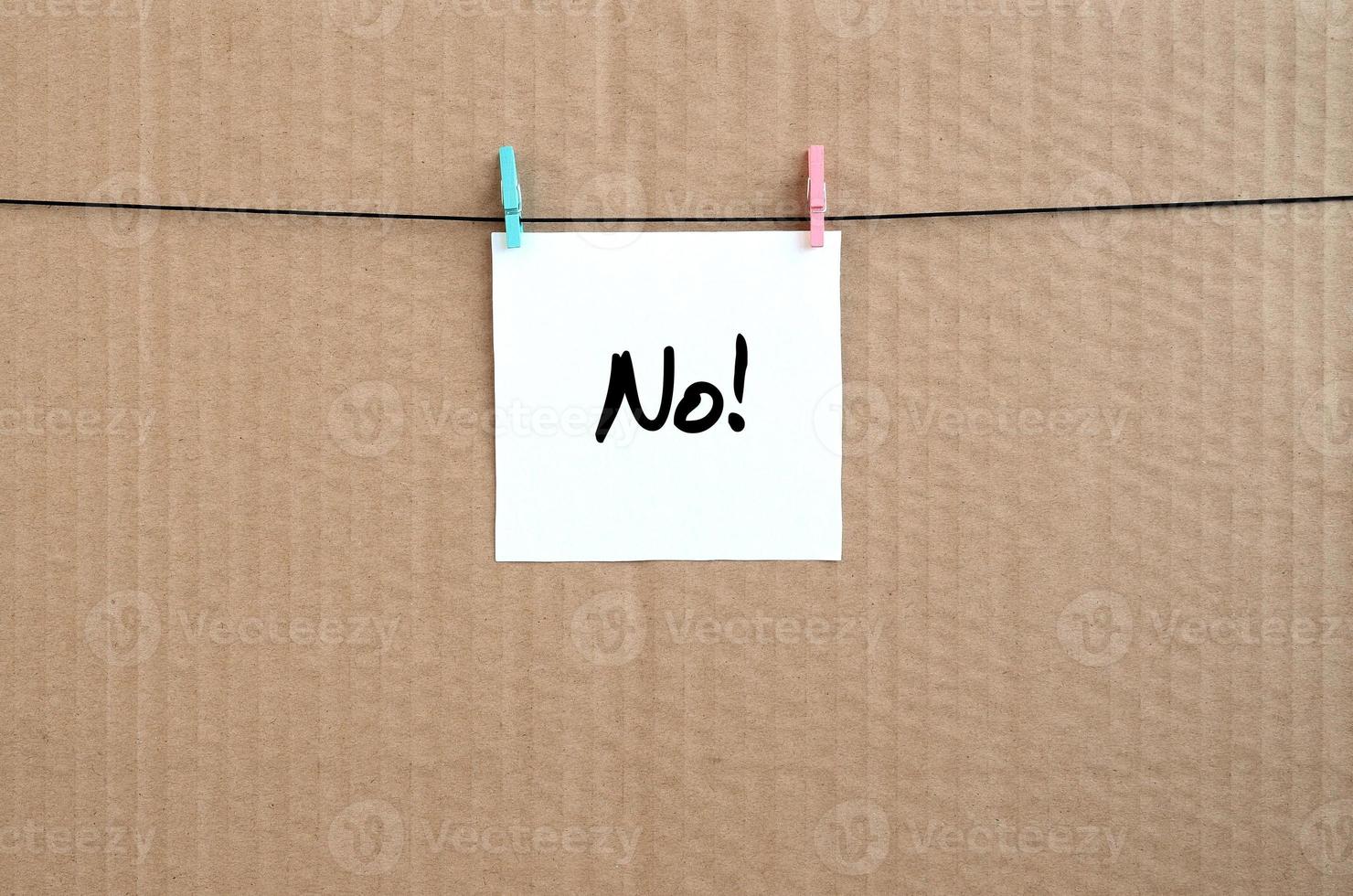 No Note is written on a white sticker that hangs with a clothespin on a rope on a background of brown cardboard photo