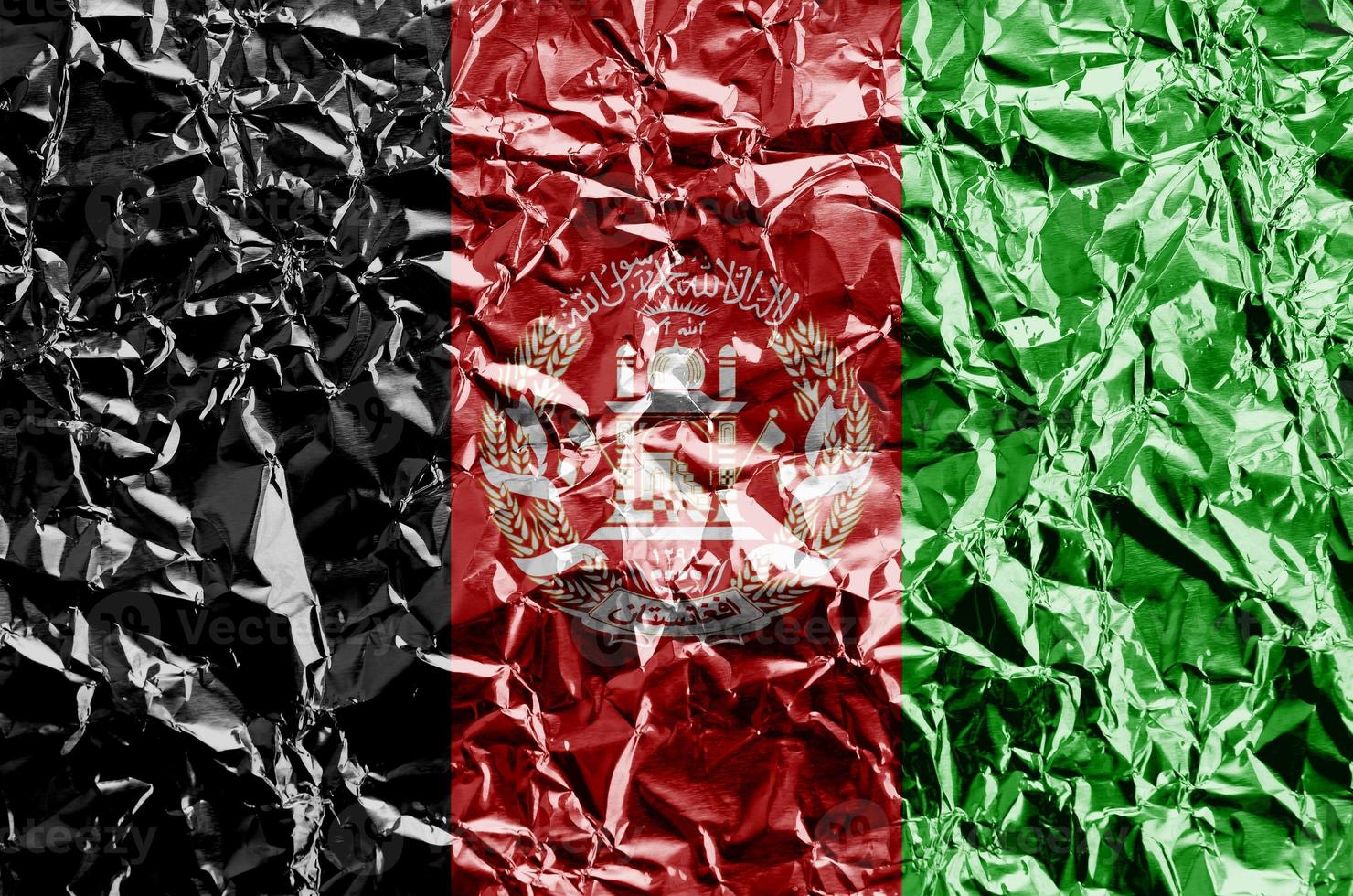 Afghanistan flag depicted in paint colors on shiny crumpled aluminium foil closeup. Textured banner on rough background photo