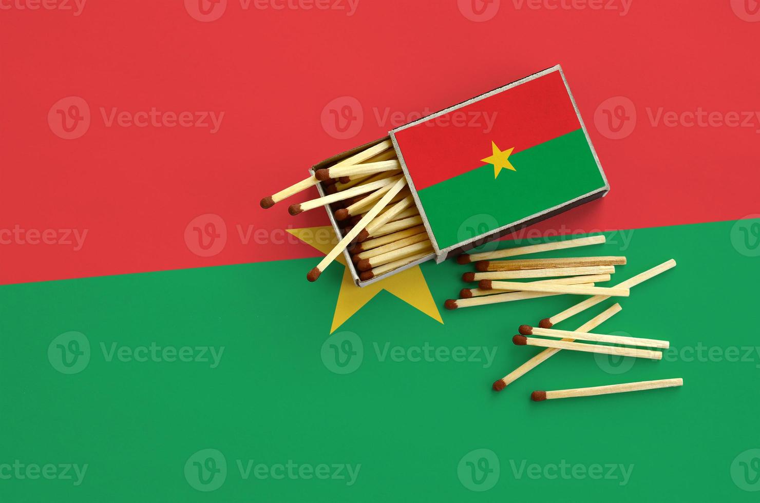 Burkina Faso flag  is shown on an open matchbox, from which several matches fall and lies on a large flag photo