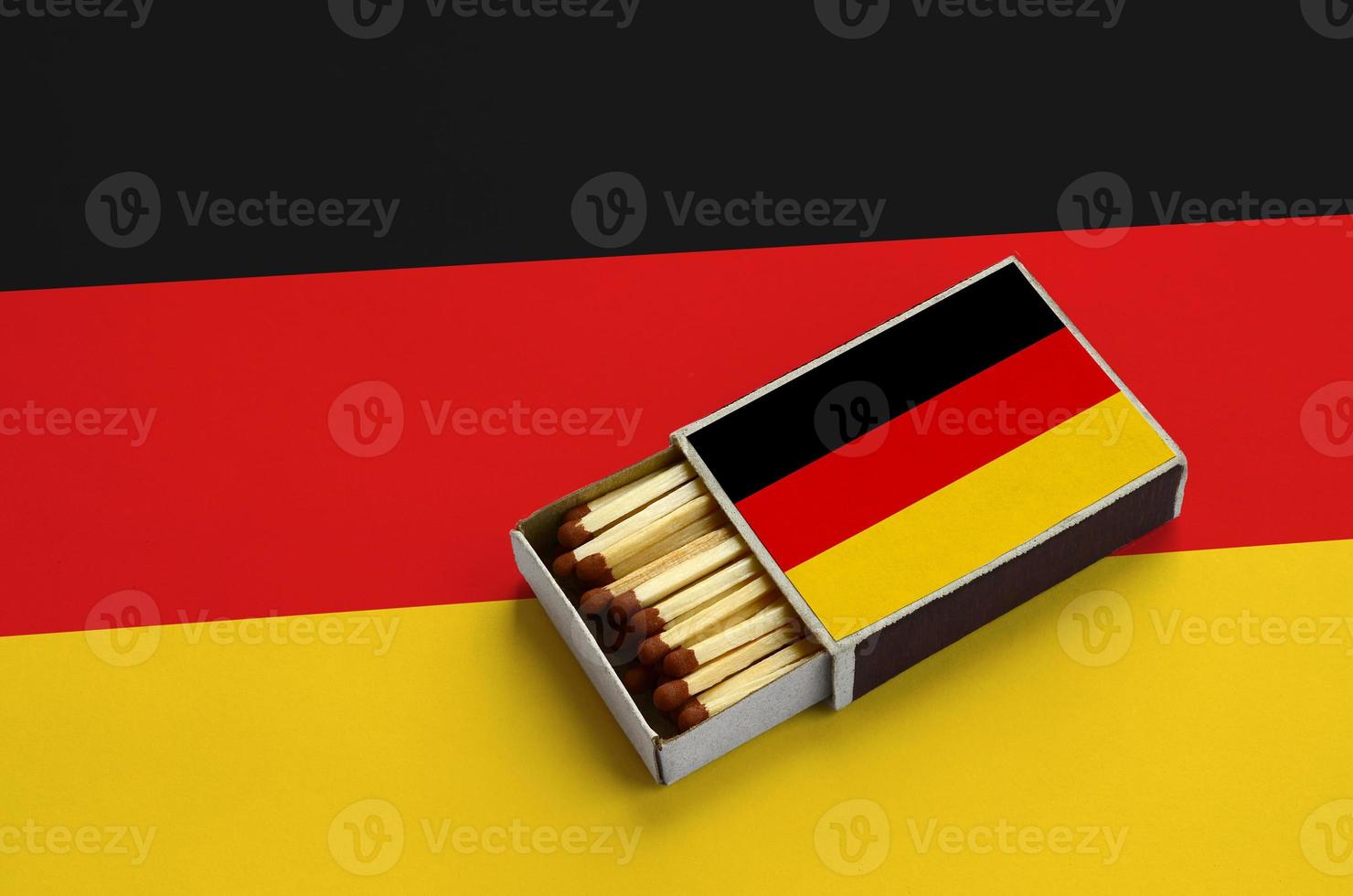 Germany flag  is shown in an open matchbox, which is filled with matches and lies on a large flag photo