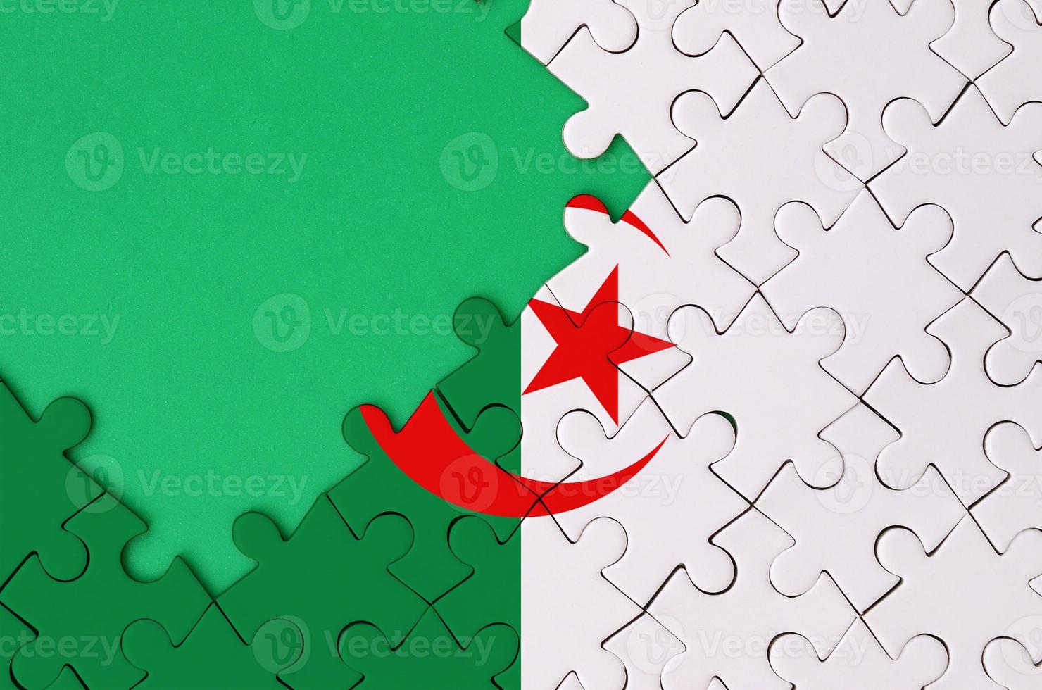 Algeria flag  is depicted on a completed jigsaw puzzle with free green copy space on the left side photo