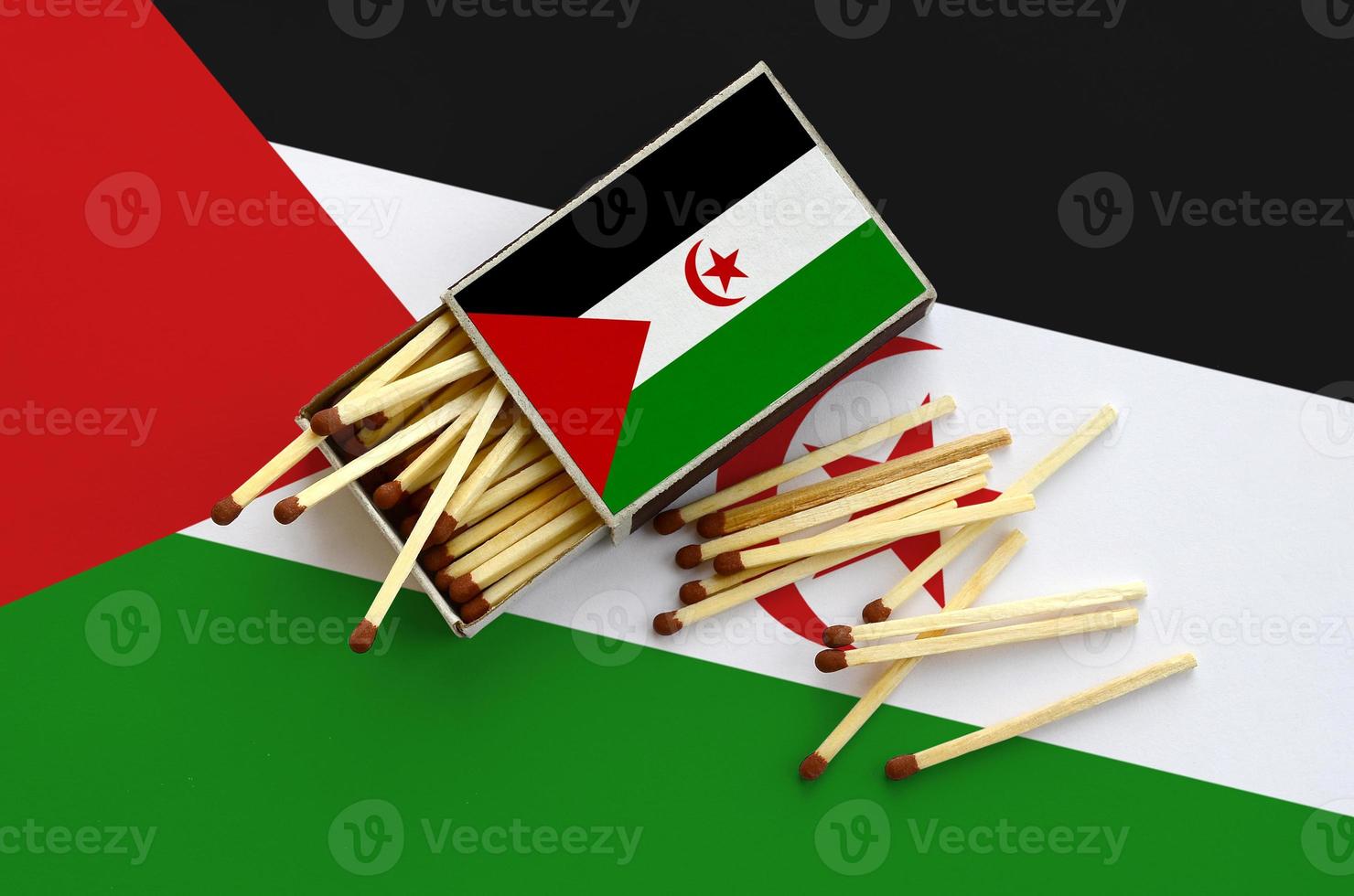 Western Sahara flag  is shown on an open matchbox, from which several matches fall and lies on a large flag photo
