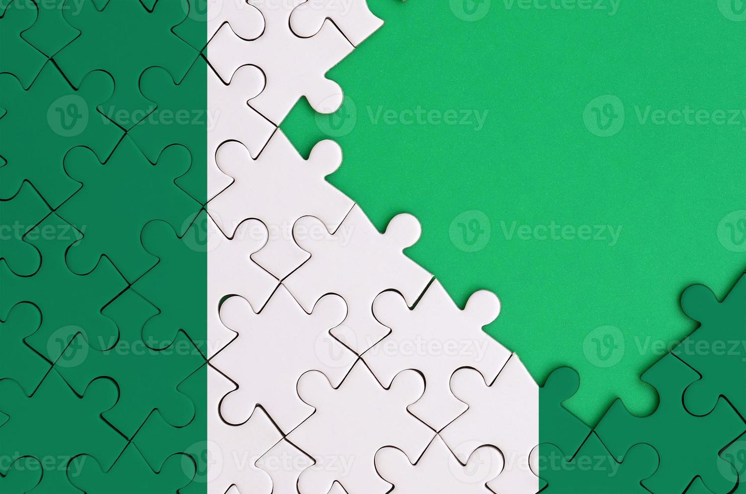 Nigeria flag  is depicted on a completed jigsaw puzzle with free green copy space on the right side photo