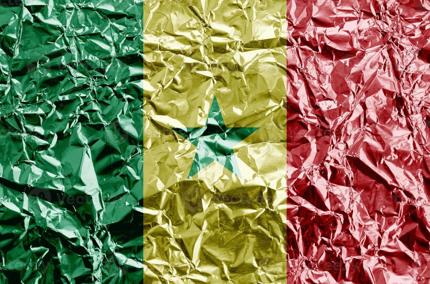 Senegal flag depicted in paint colors on shiny crumpled aluminium foil closeup. Textured banner on rough background photo