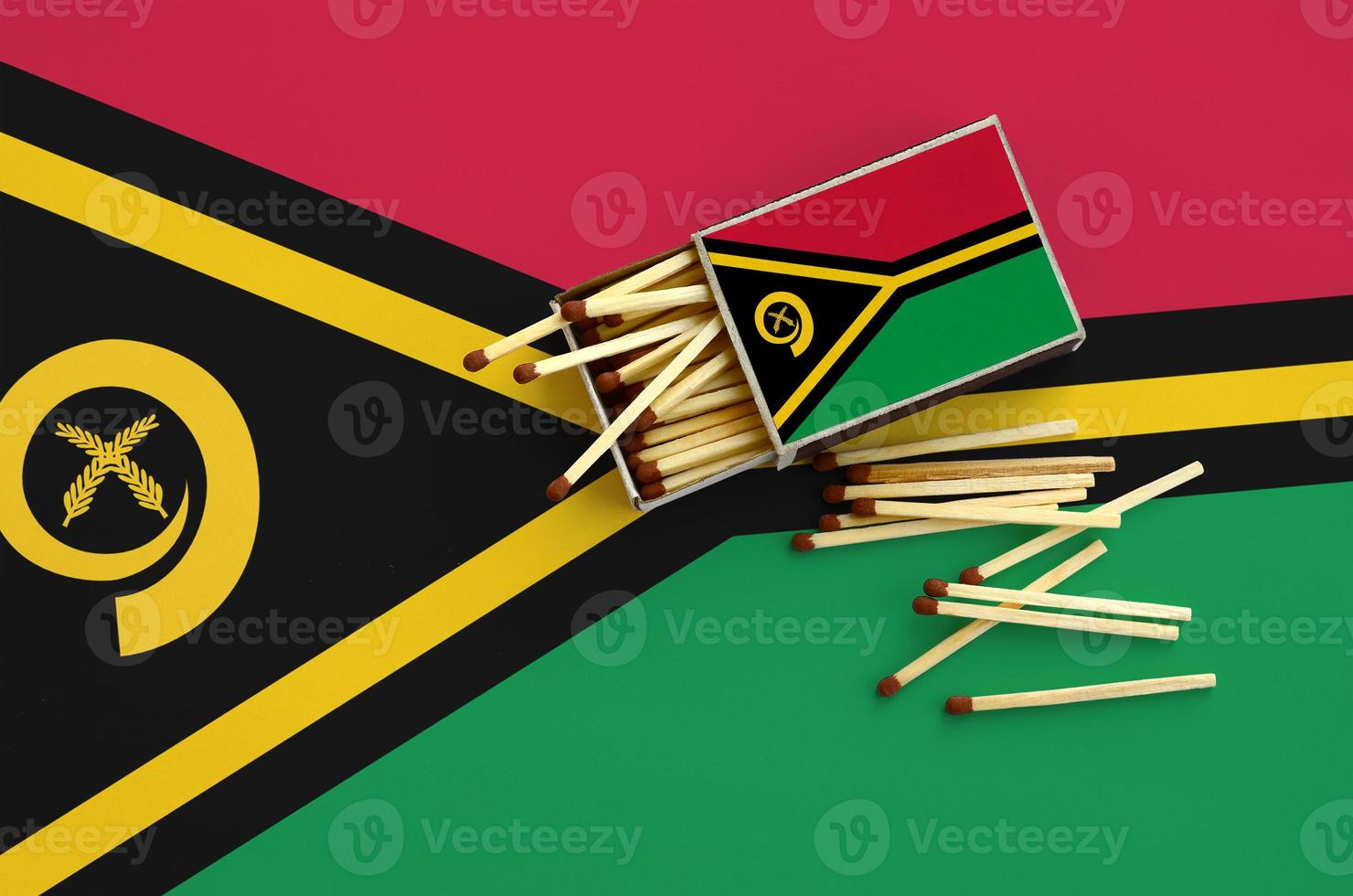 Vanuatu flag  is shown on an open matchbox, from which several matches fall and lies on a large flag photo