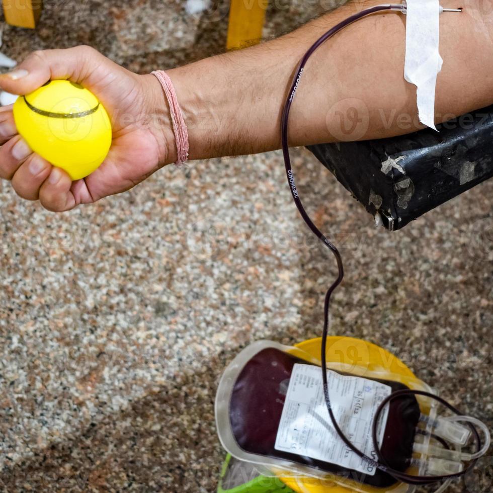 Blood donor at Blood donation camp held with a bouncy ball holding in hand at Balaji Temple, Vivek Vihar, Delhi, India, Image for World blood donor day on June 14 every year, Blood Donation Camp photo