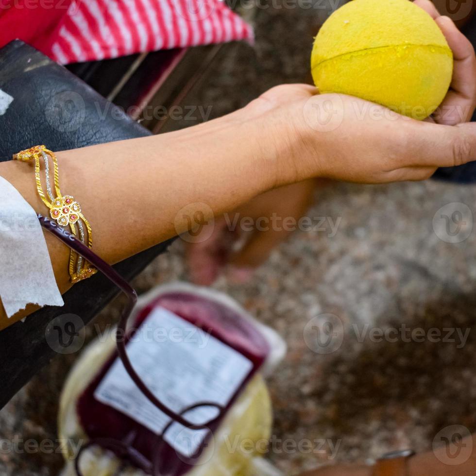 Blood donor at Blood donation camp held with a bouncy ball holding in hand at Balaji Temple, Vivek Vihar, Delhi, India, Image for World blood donor day on June 14 every year, Blood Donation Camp photo