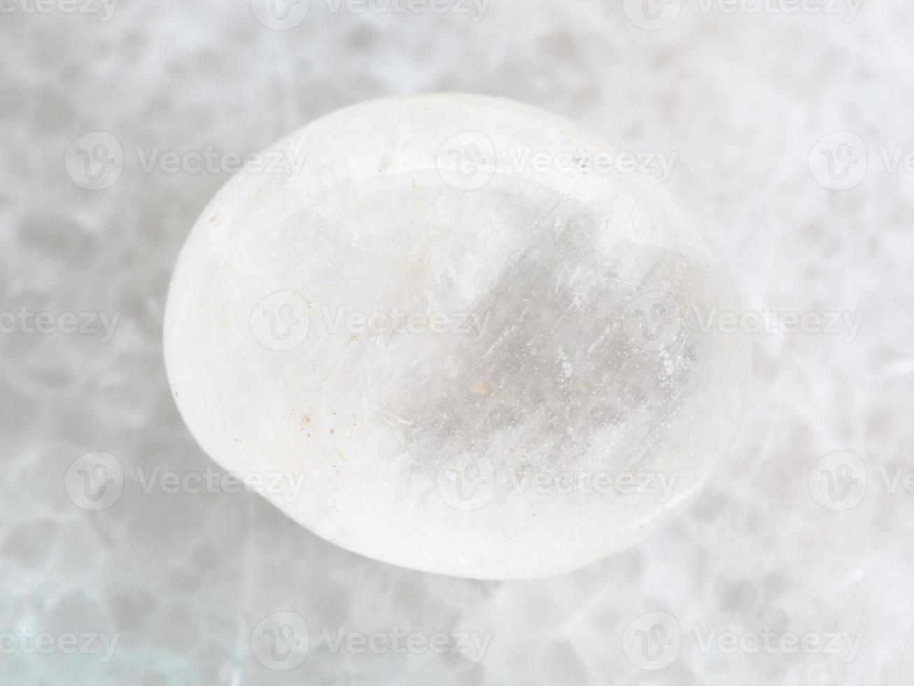 piedra preciosa de ágata blanca caída sobre mármol blanco foto