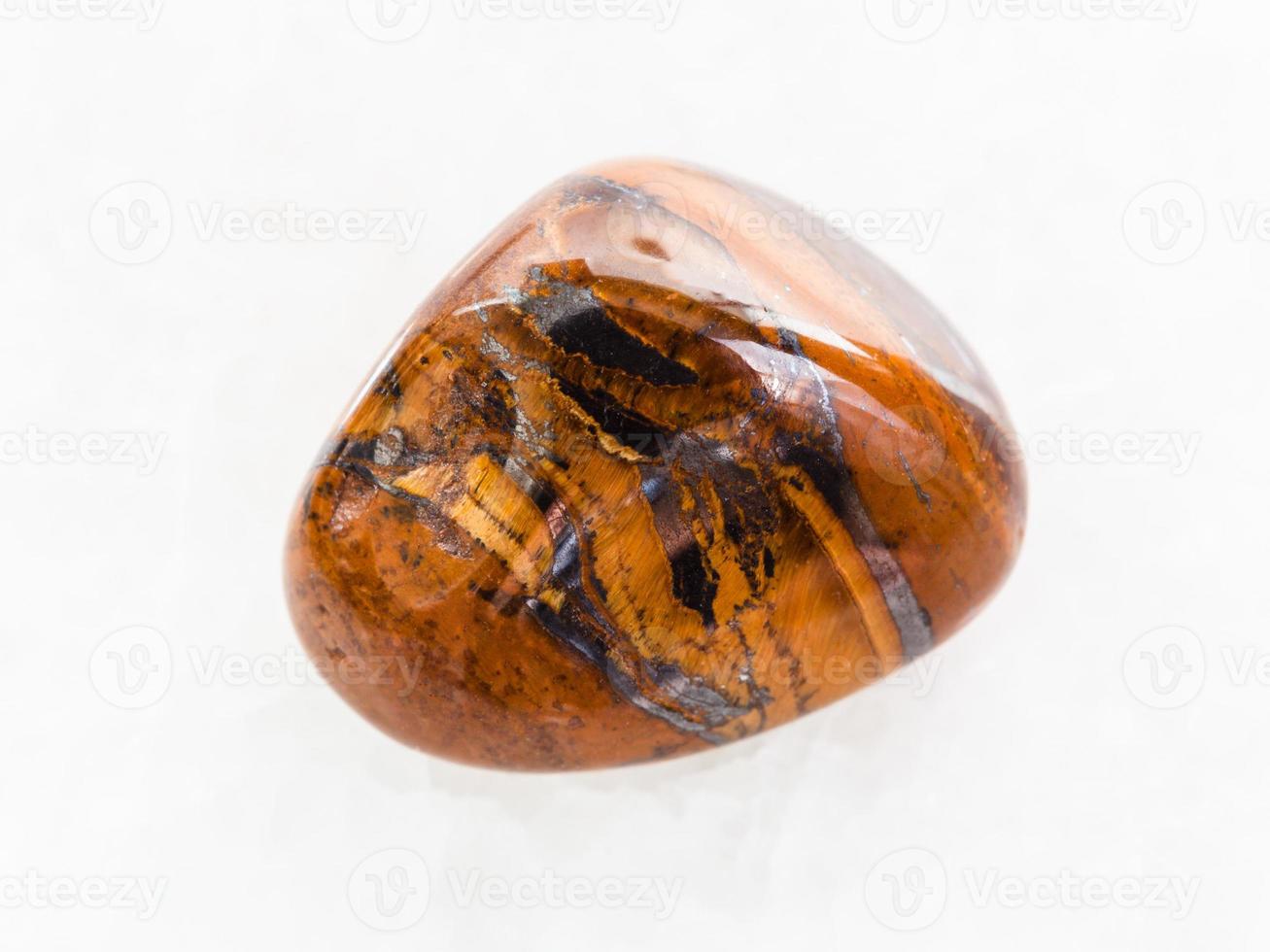 polished tigers eye gemstone on white marble photo