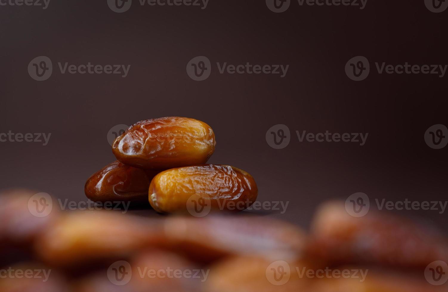 Dates lie on the background of other dates. Ripe dried dates. photo