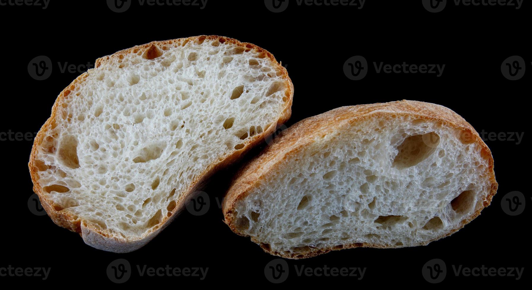 Ciabatta, a loaf of bread cut in half isolated on a black background. photo