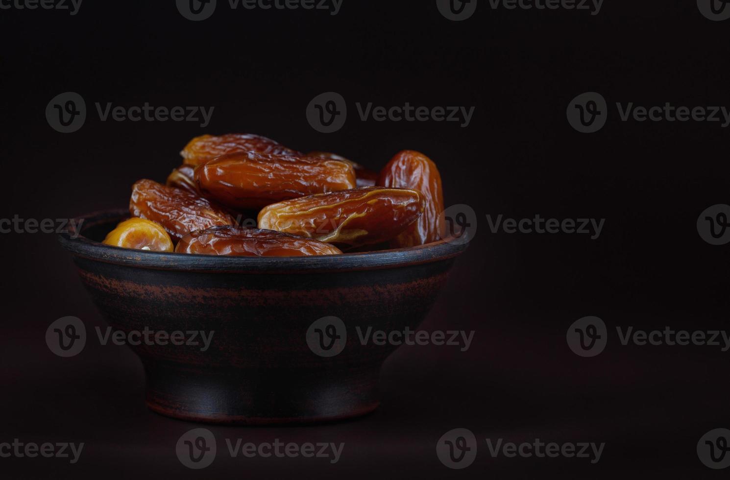 Clay cup full of ripe dried dates on a brown background. photo
