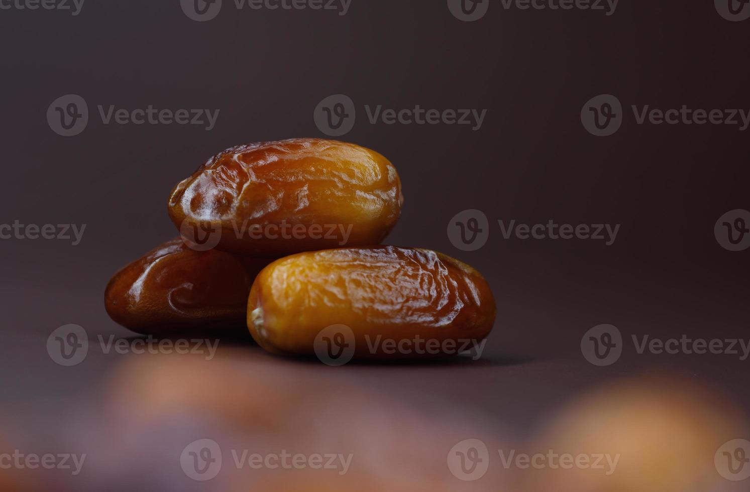 Three ripe delicious dates lie on a brown background. photo