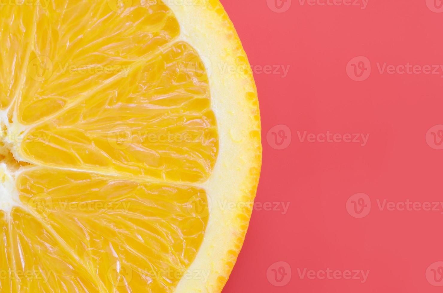 Top view of a one orange fruit slice on bright background in red color. A saturated citrus texture image photo