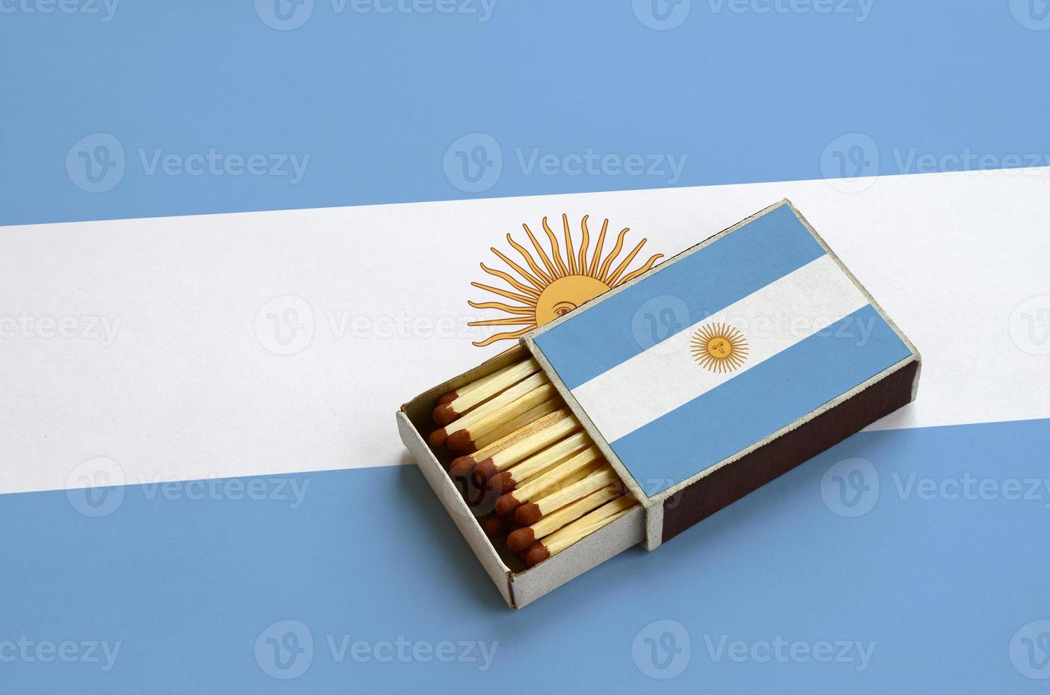 la bandera argentina se muestra en una caja de fósforos abierta, que está llena de fósforos y se encuentra en una bandera grande foto