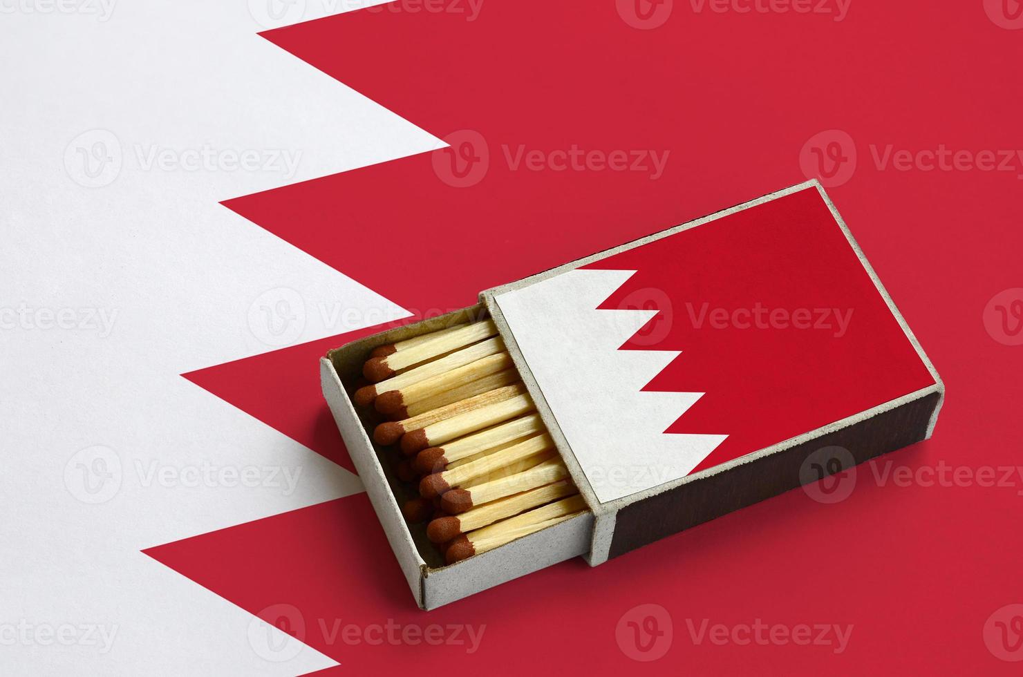 Bahrain flag  is shown in an open matchbox, which is filled with matches and lies on a large flag photo