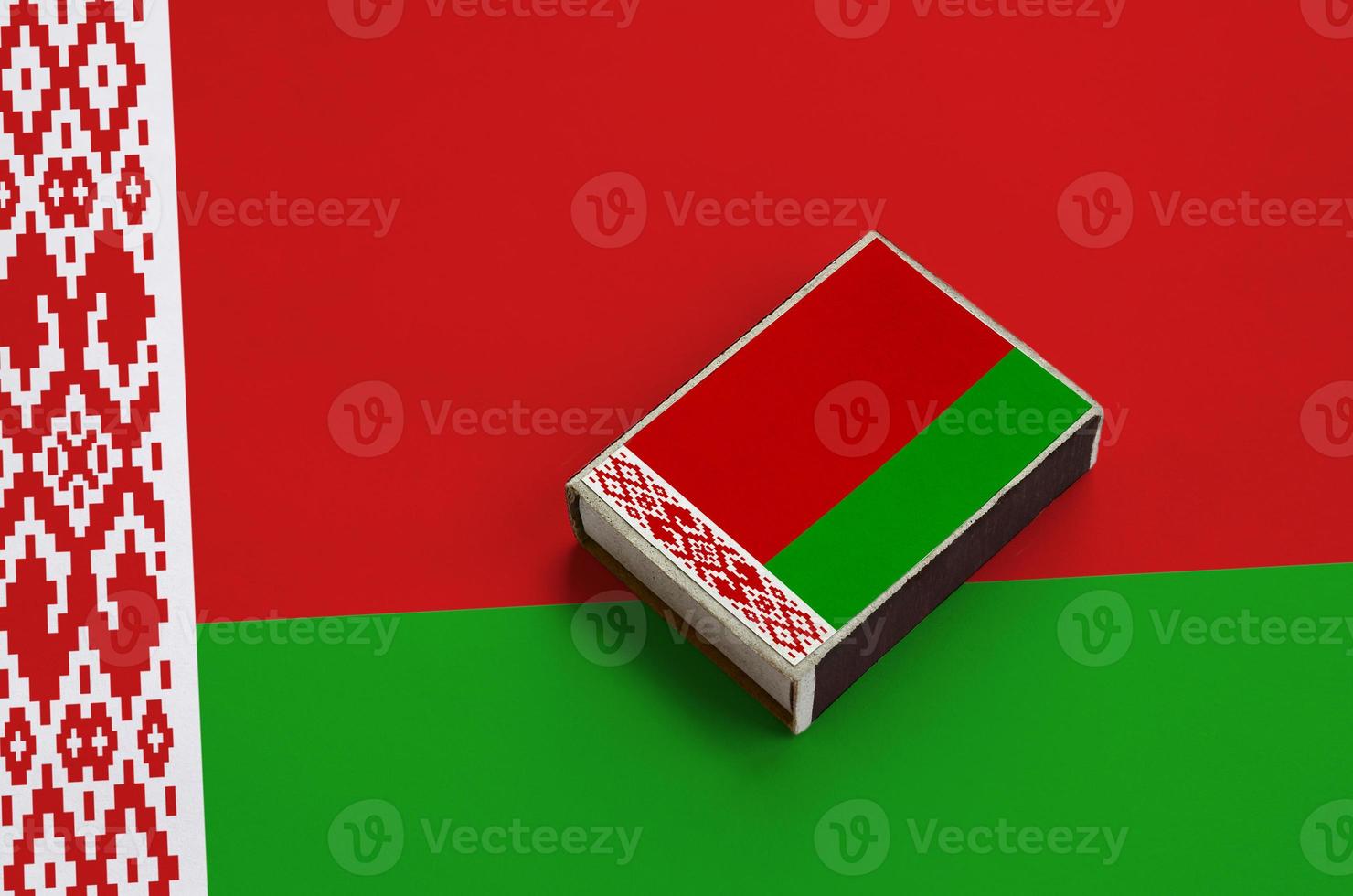 Belarus flag  is pictured on a matchbox that lies on a large flag photo