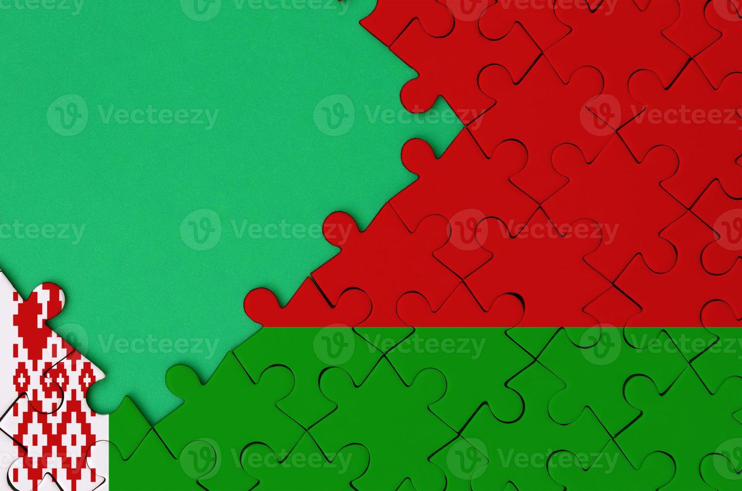 Belarus flag  is depicted on a completed jigsaw puzzle with free green copy space on the left side photo