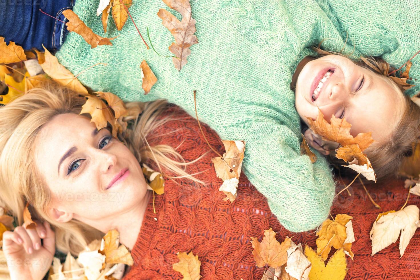 Girl and mom lying on autumn leaves photo