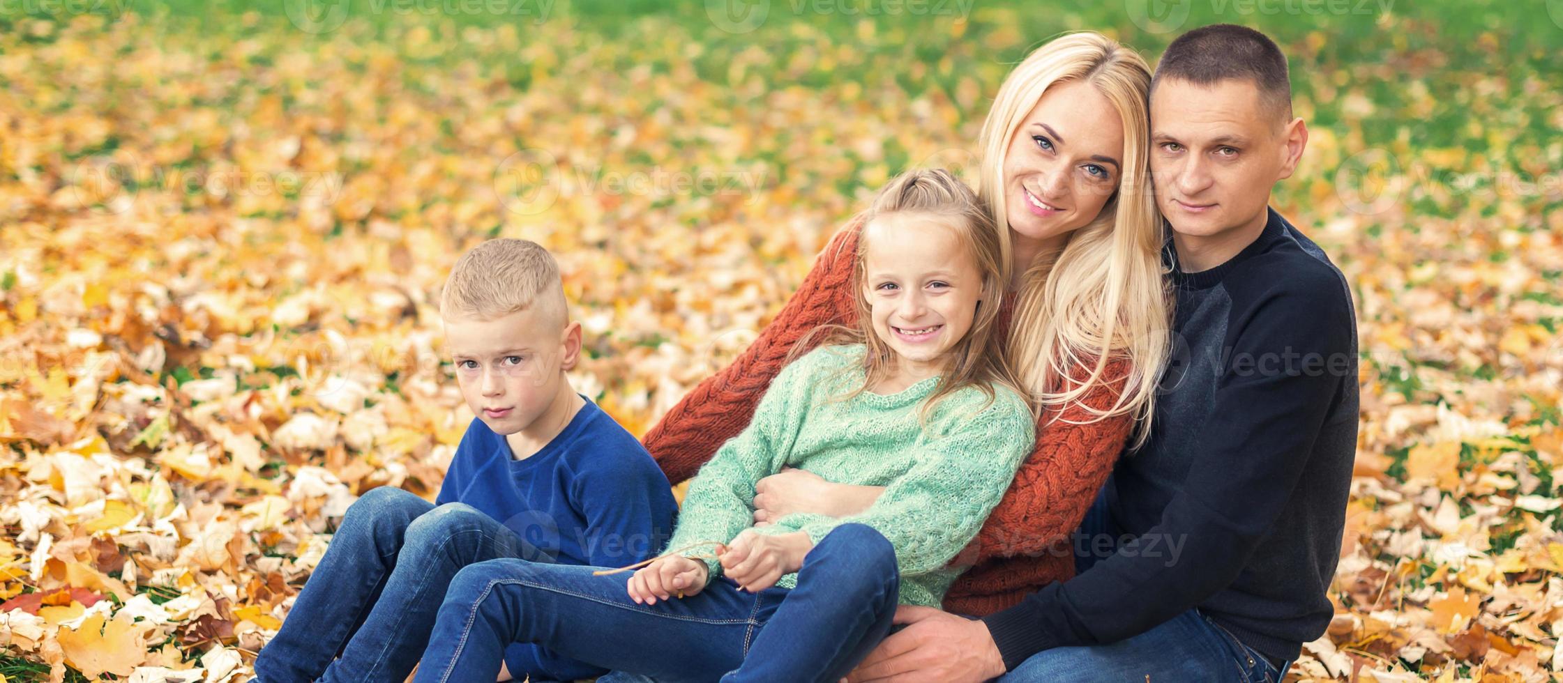 Portrait of young family sitting in autumn leaves photo