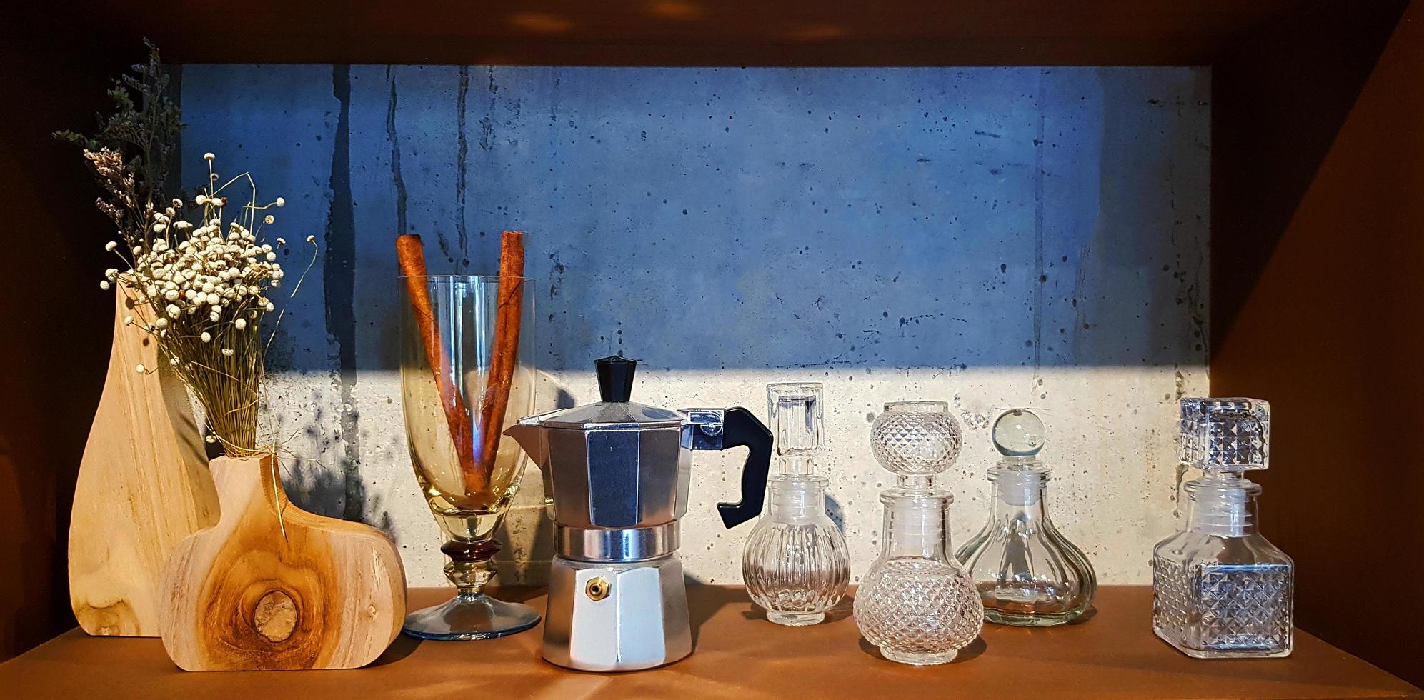 Group of object on wooden shelf with Moka pot, many glass bottle and dry flower in jar for sale or show with loft concrete wall background. photo