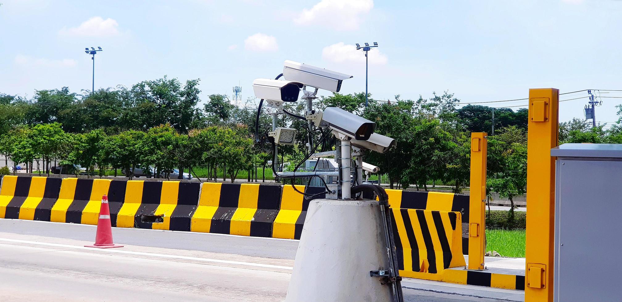 Group of CCTV camera installed for recording accident on road or street with painted yellow and black barrier, . tree and sky background. Protection, Observe traffic and keeping transportation. photo