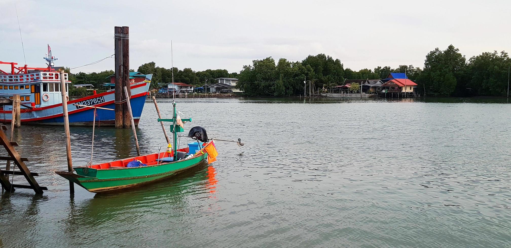 bote de cola larga verde en el río con iluminación de primer plano y cielo, verde con fondo de casa en tono vintage con espacio de copia. estilo de vida rural con vistas a la naturaleza y al paisaje. foto