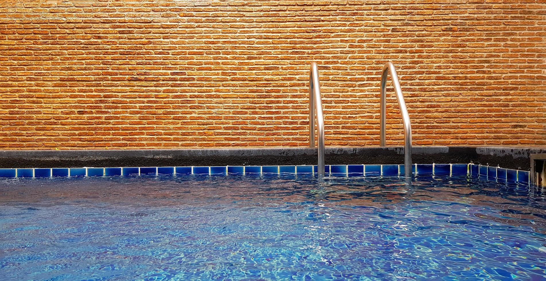 piscina con escalera y fondo de pared de ladrillo con espacio para copiar. interiorismo y estructura. foto