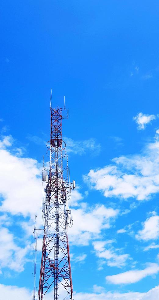 telecomunicaciones rojas y blancas, televisión de difusión, televisión digital, radio, transmisión, microondas o torre móvil con cielo azul y fondo de nubes y espacio de copia. tecnología y equipos de telecomunicaciones foto