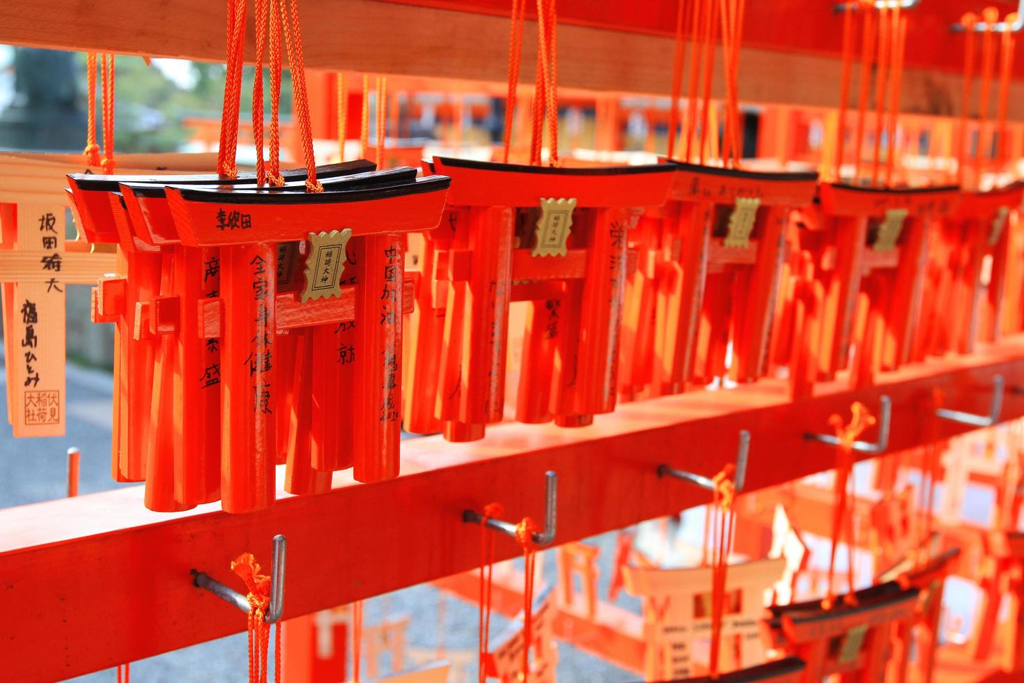 Kyoto, Japan - February 25, 2020 Many small Torii Gate hanging on red wooden hanger at Fushimi Inanari Shrine. People write blessings on amulets and prayed to be true. photo
