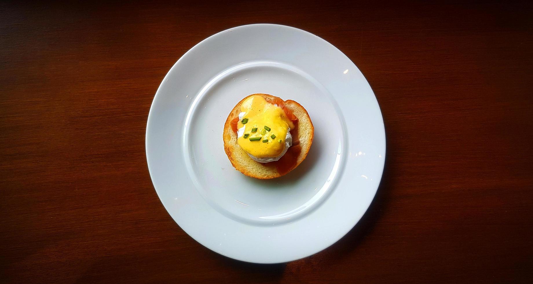 Flat lay of bread with poached egg, bacon and sweet sauce on top in dish. Top view of delicious meal of breakfast on white plate in American style. Food on table. photo