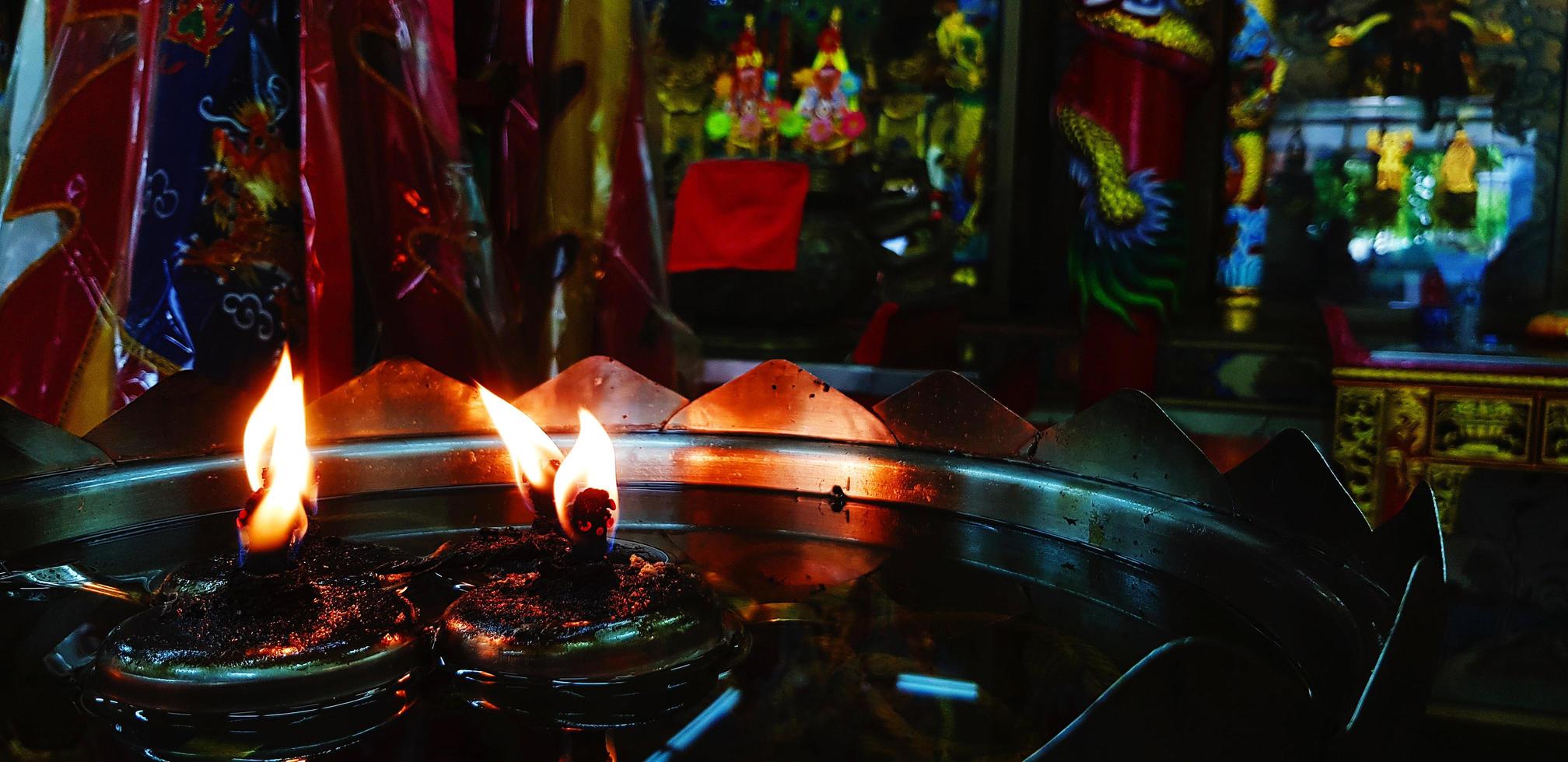 muchos vasos de luz de las velas en bandeja roja por respeto santo en la mesa de acero inoxidable en el templo chino o tailandés. religión, creencia de la gente. foto