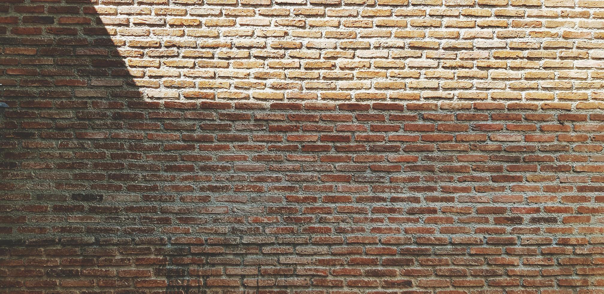 Brown or red brick wall with shadow for background. Art and Pattern wallpaper. Rough and Grunge exterior or interior design with copy space photo