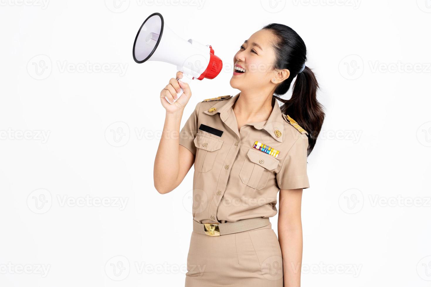 sonrisa profesora asiática en uniforme del gobierno tailandés está de pie y gritando con un megáfono sobre fondo blanco. foto