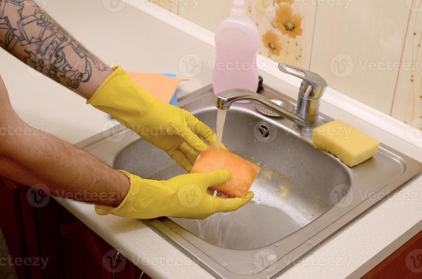 Person or householder cleaning the kitchen sink with sponge in close up view photo