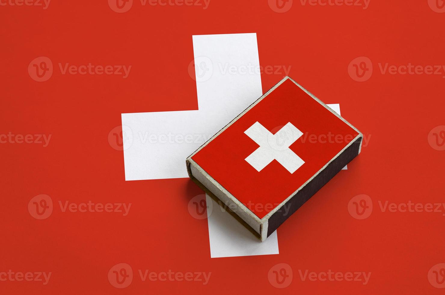 Switzerland flag  is pictured on a matchbox that lies on a large flag photo