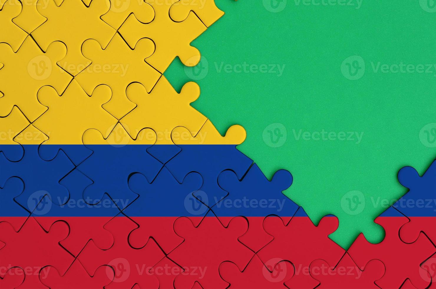 Colombia flag  is depicted on a completed jigsaw puzzle with free green copy space on the right side photo